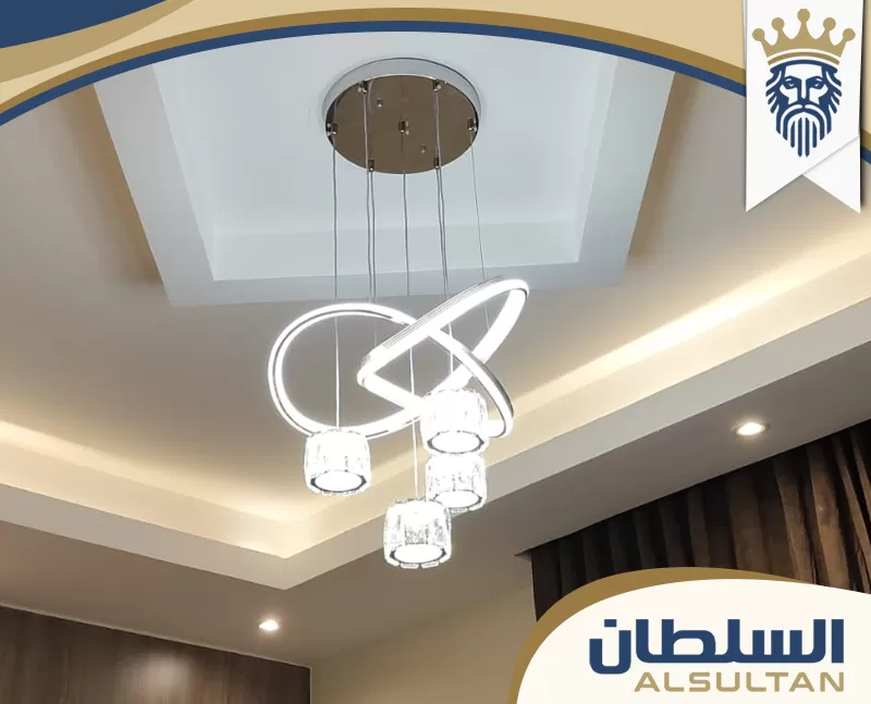 سقف جبس بورد بتصميم مستطيل بسيط، يتوسطه ثريا دائرية حديثة مع إضاءة مخفية، وسبوت لايت موزع حول السقف.
