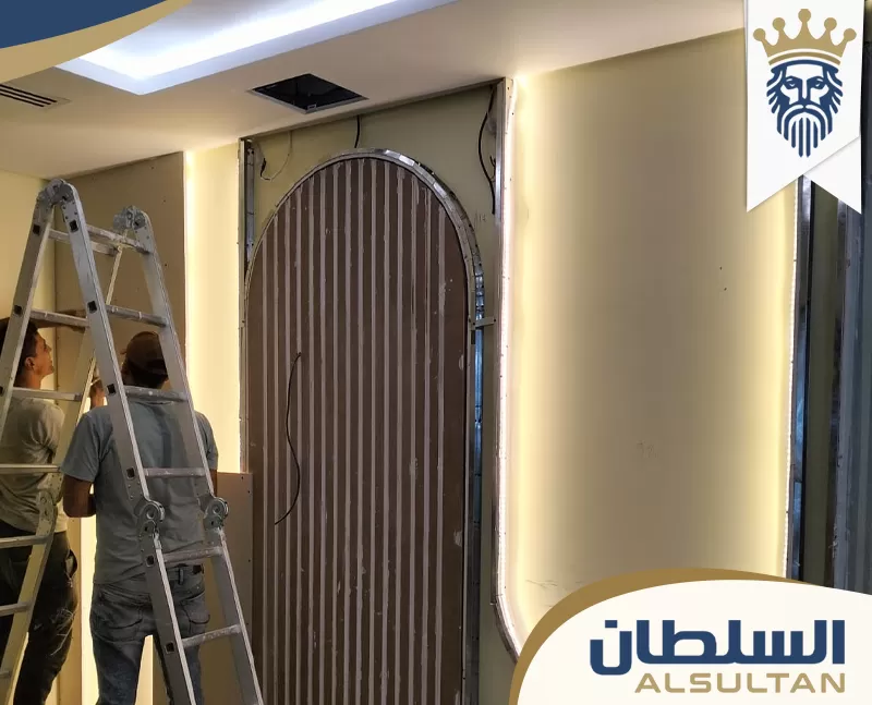 تنفيذ ديكور جبس بورد حول مدخل مقوس أثناء التركيب، مع إضاءة مخفية وهيكل معدني يحدد شكل القوس.