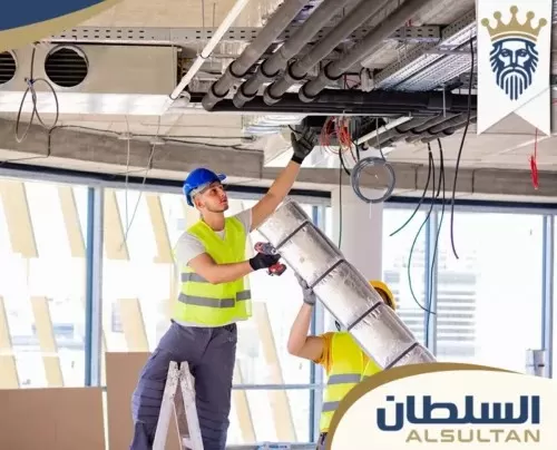 رجلان يقومان بإصلاح مواسير المكيف في مبنى مكاتب، ويركزان على صيانة أجهزة التكييف في دبي.